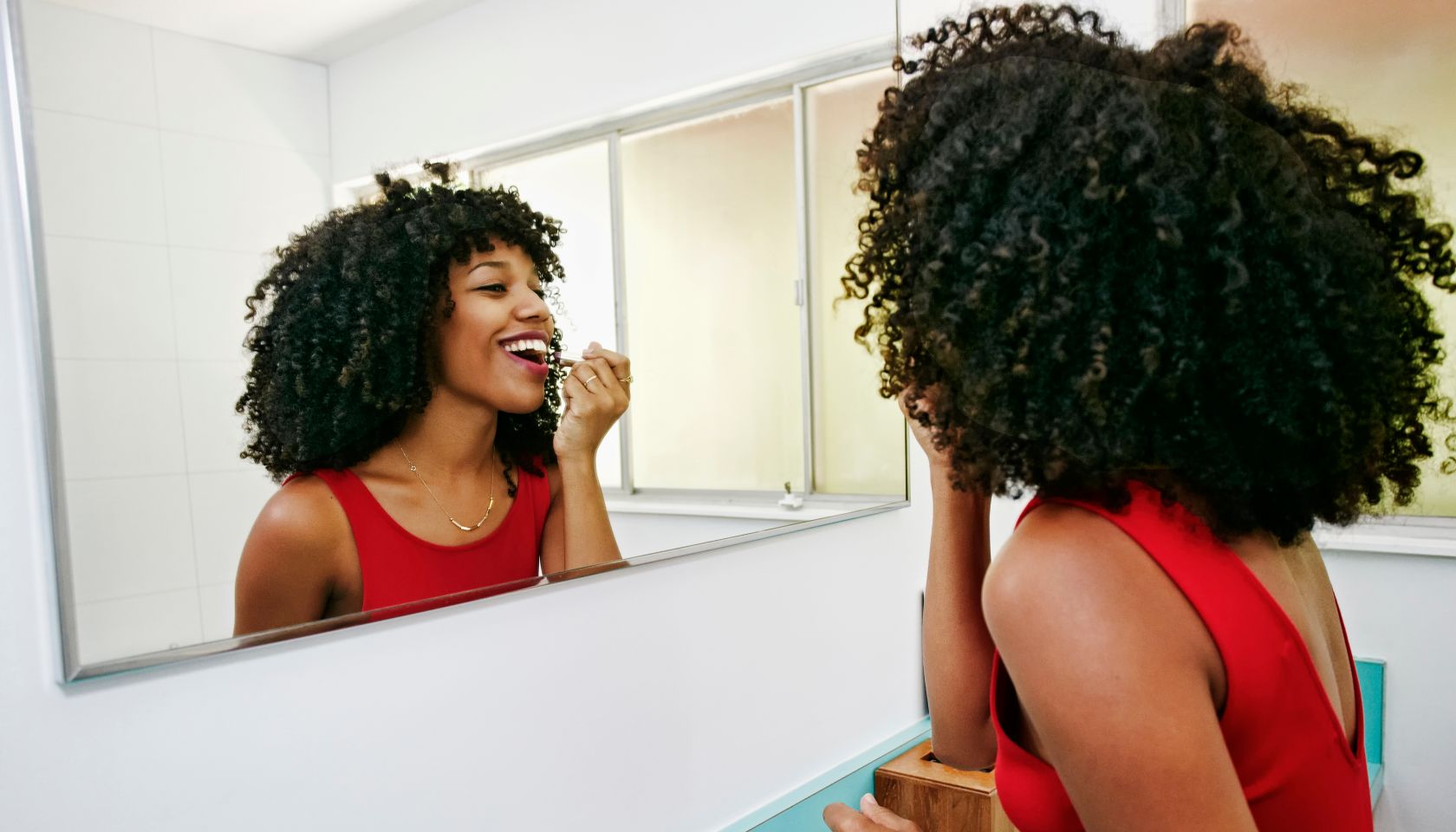 Mixed race woman applying makeup in mirror