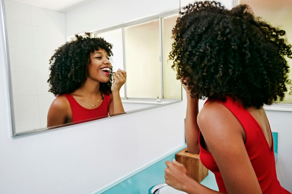 Mixed race woman applying makeup in mirror