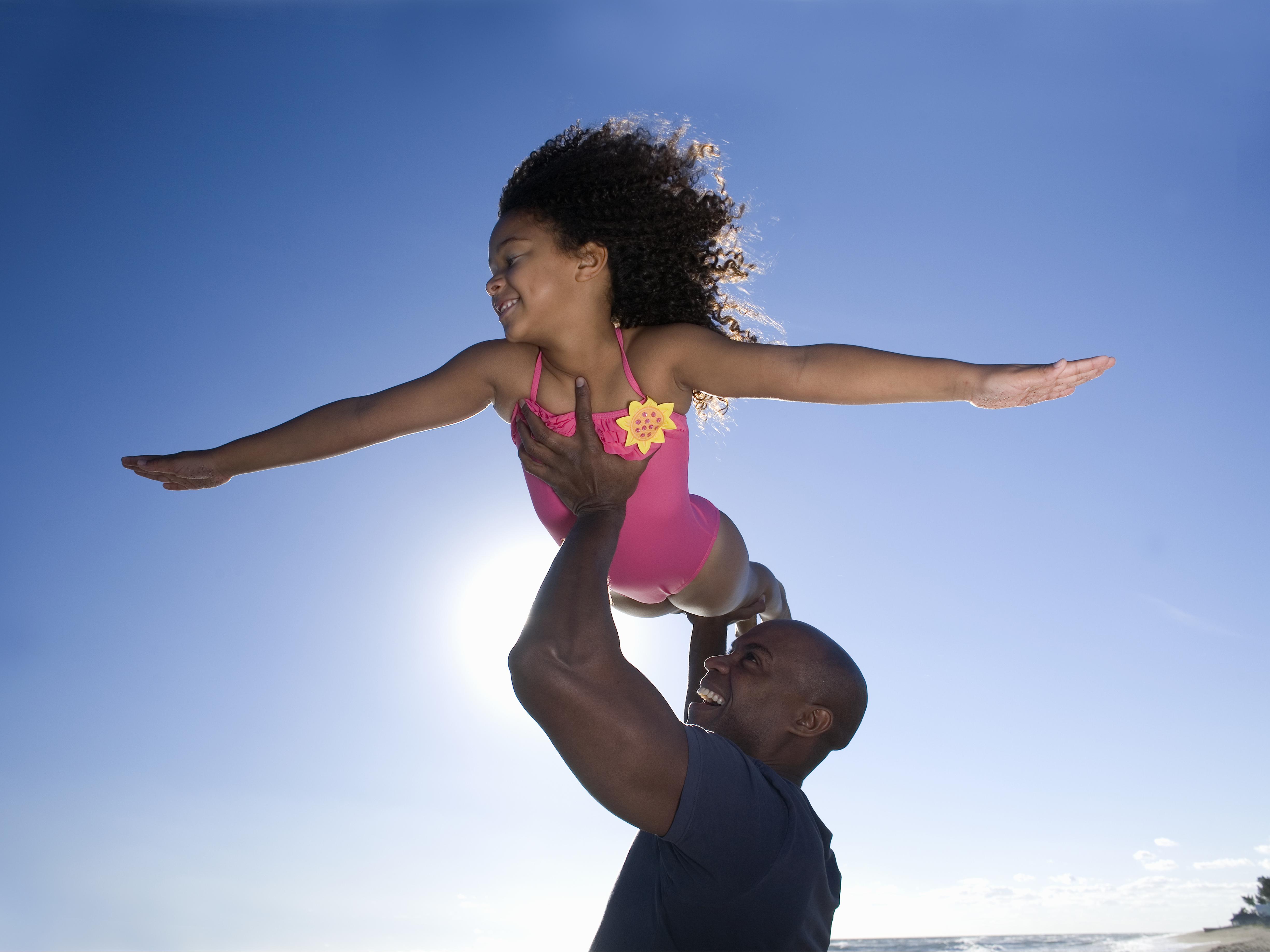 Father carrying daughter (6-7) on beach