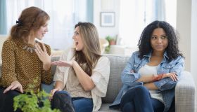 Chatting women ignoring upset friend on sofa