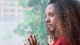 Black woman looking out rainy window