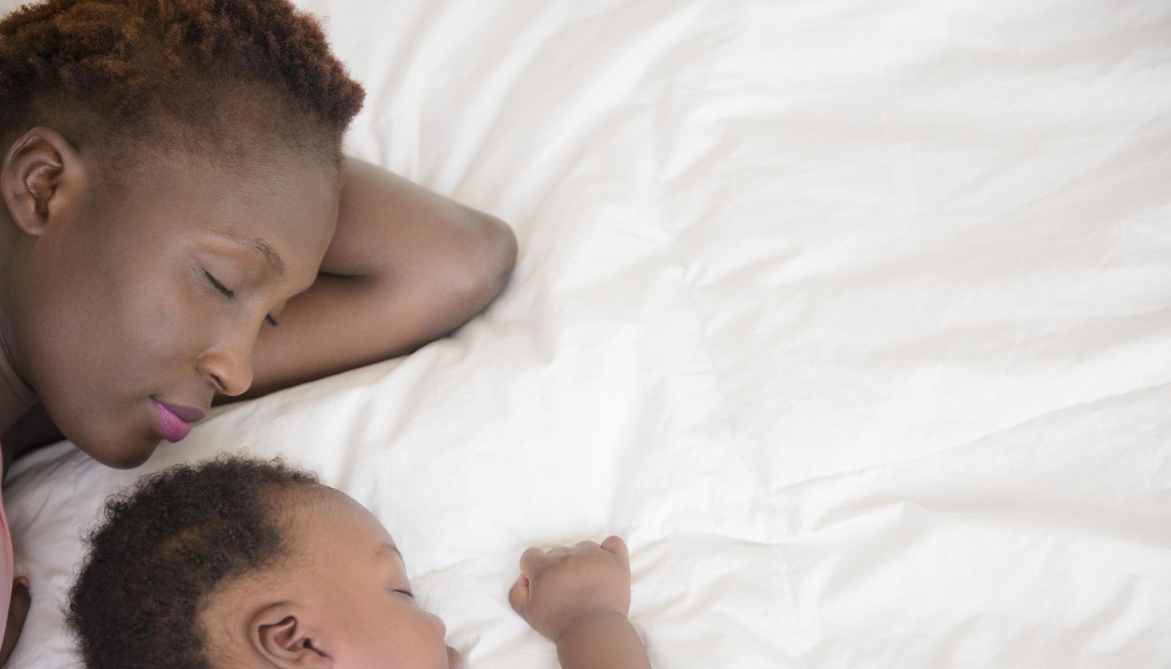 Black mother and son sleeping on bed