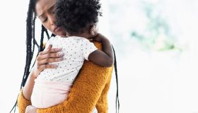 Black woman holding and comforting baby daughter