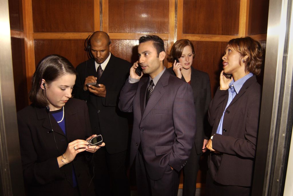 Businesspeople using cellular phones in elevator