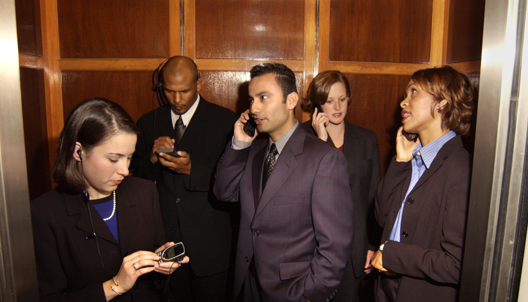 Businesspeople using cellular phones in elevator