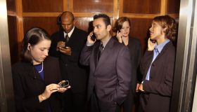 Businesspeople using cellular phones in elevator