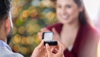 Closeup of ring box as young man proposes to girlfriend