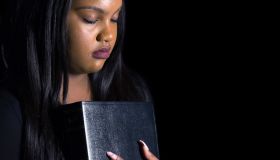 Close-Up Of Young Woman Praying Against Black Background