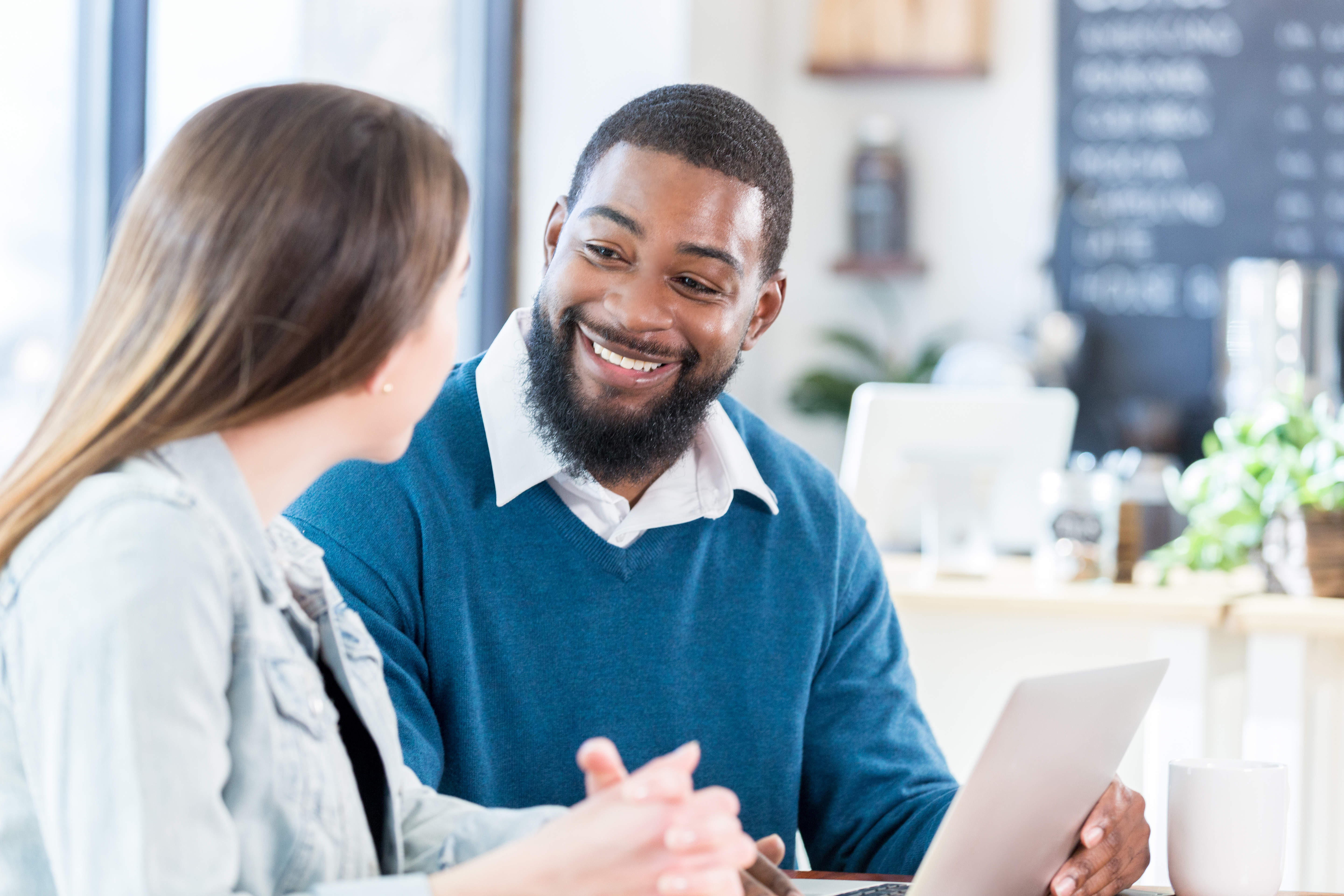 Mid adult businessman has discussion with woman in coffee shop