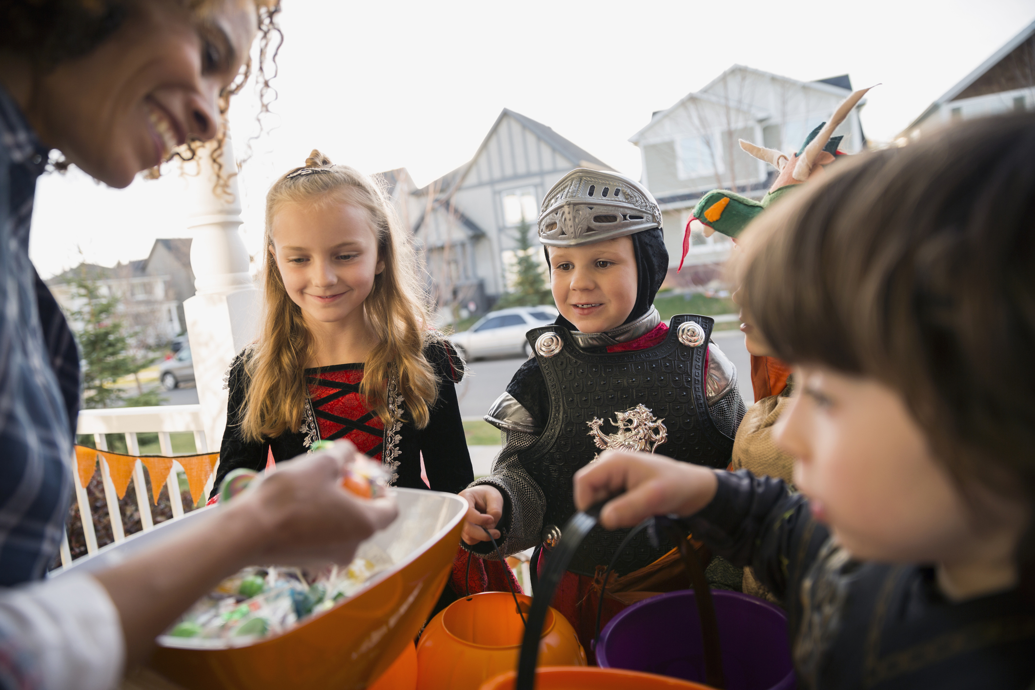 Woman candy greeting trick or treaters front stoop