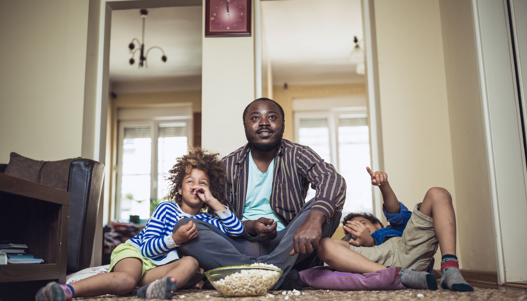 Kids watching movie with their father at home.