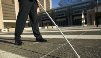 low angle low section view of a blind man walking with the aid of a white stick