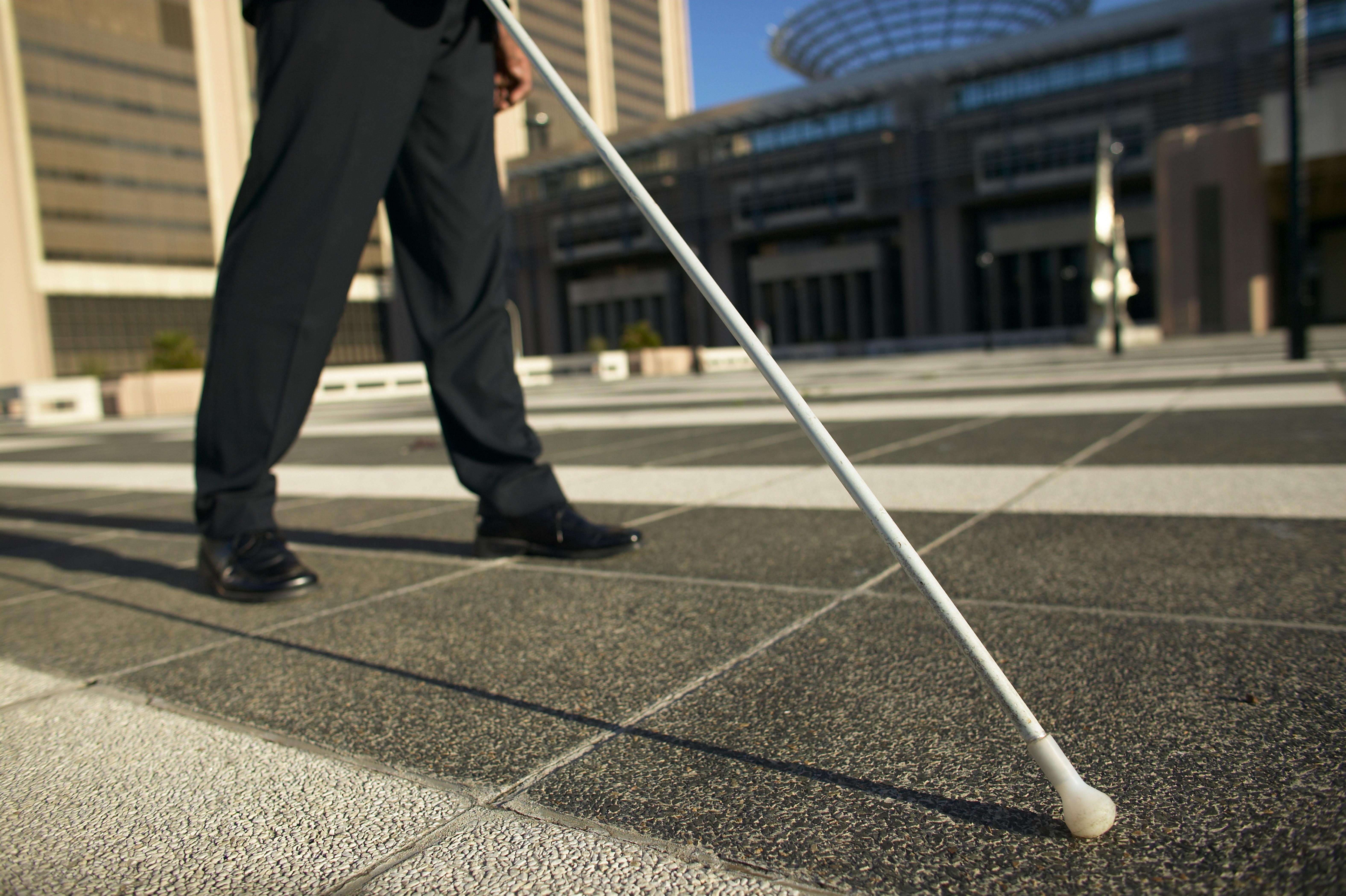 low angle low section view of a blind man walking with the aid of a white stick