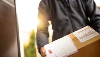 Courier holding cardboard box for delivery