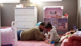 Father and daughter playing by her dolls house