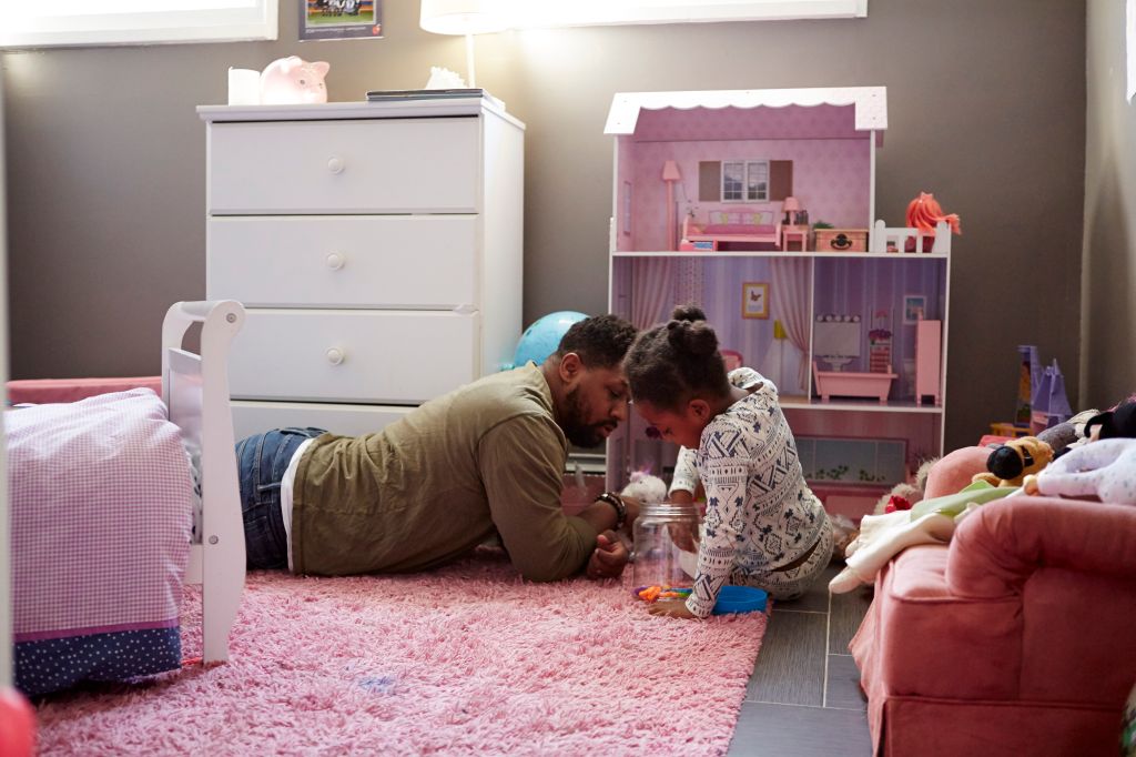 Father and daughter playing by her dolls house