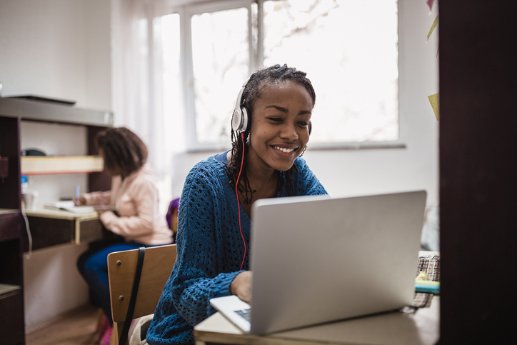 Young African female student , relaxing and listening music in a University campus room