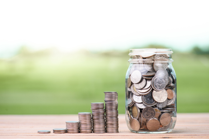 Close-Up Of Coins Stack By Jar On Table