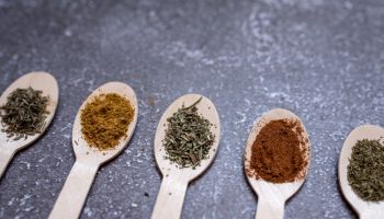 spices in wooden spoons on a gray background. cooking, a place to copy