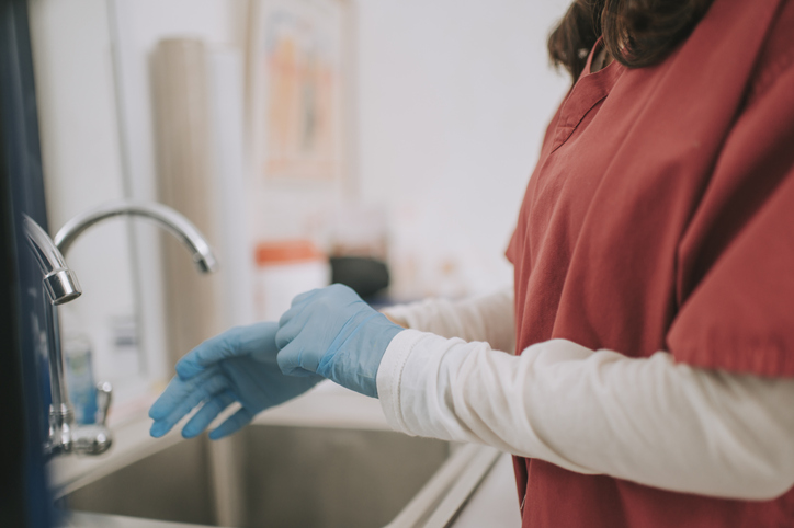 asian chinese dentist with medical scrub wearing surgical glove getting ready for surgery at dentist office