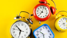 A Collection Of Colorful Alarm Clocks In Retro and Vintage Style On A Bright Yellow Background. The concept of the speed and rapidity of Time and the Flow of Life. Banner. Copy space.