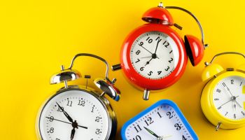 A Collection Of Colorful Alarm Clocks In Retro and Vintage Style On A Bright Yellow Background. The concept of the speed and rapidity of Time and the Flow of Life. Banner. Copy space.