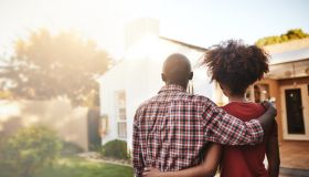 Back view, black couple and hug outdoor at house, real estate and new loan for luxury home. Man, woman and people in front of property investment, moving and dream neighborhood for building mortgage