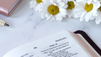 Open holy bible book, Psalm 10 verses with flowers on white marble table