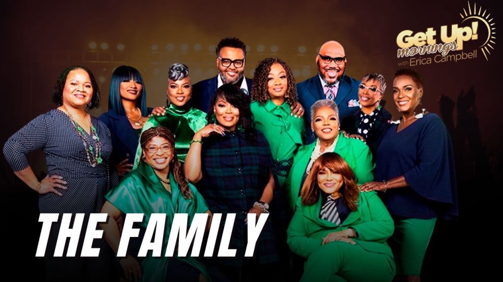 A group of 11 people, mostly women, wearing green and blue outfits, posing together in front of a "Get Up! Mornings with Erica Campbell" backdrop.